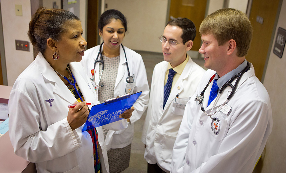 4 people in white coats in hospital lobby