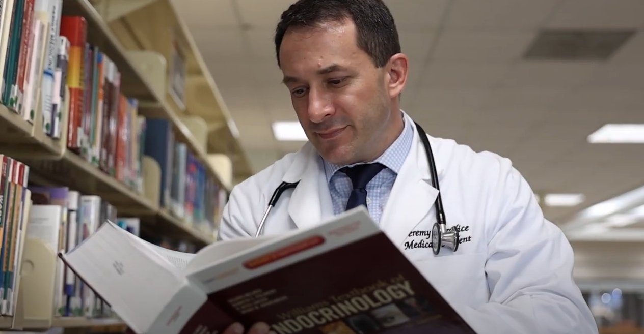 Student in white coat reading book