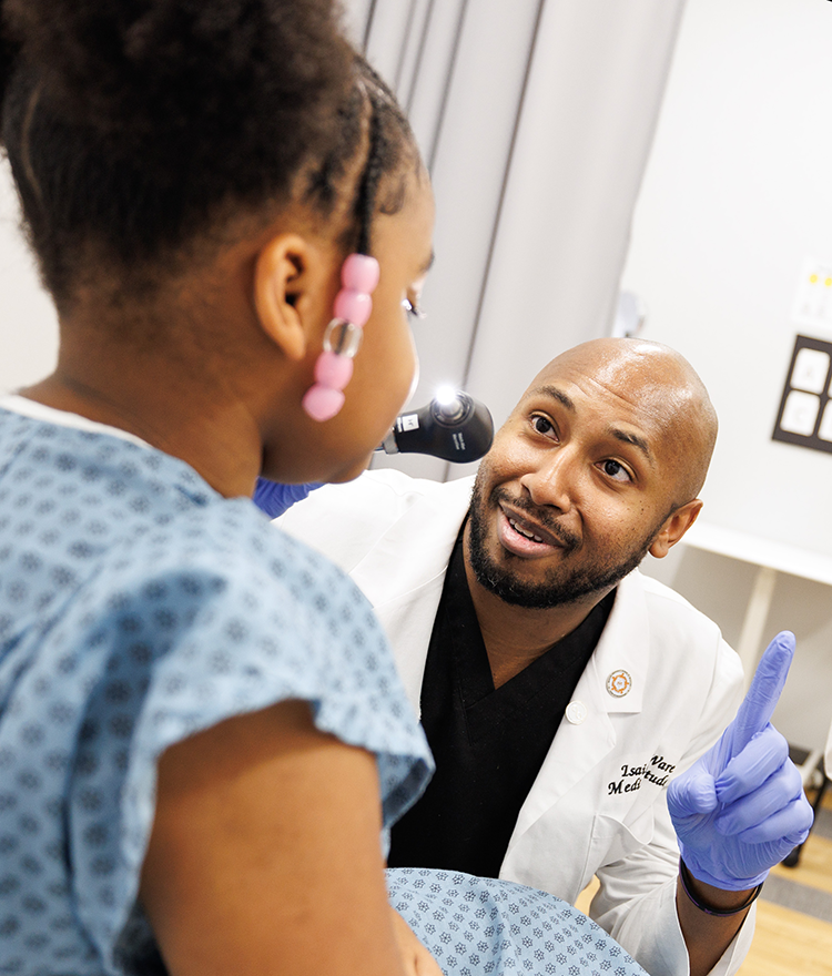 Student with young clinical skills patient holding up his finger for her to look at