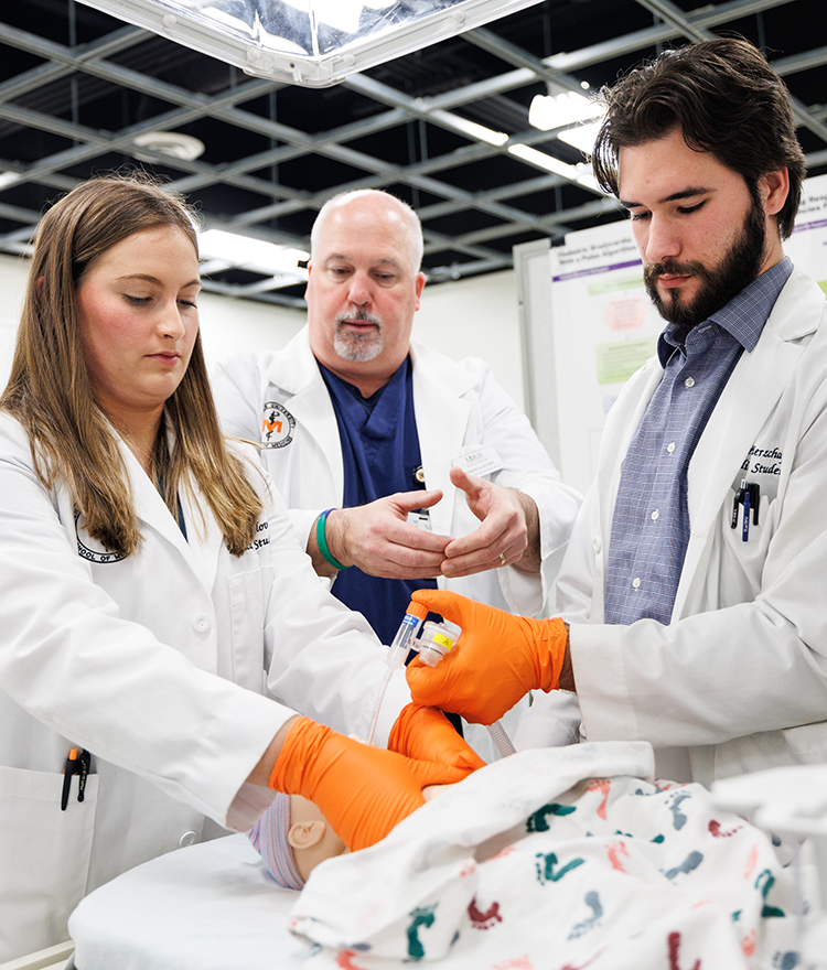 Professor and two students in simulation lab working on model baby.