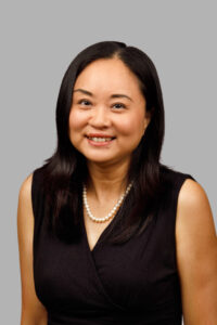 professional headshot of a smiling woman with black hair and grey background