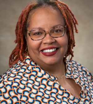 Professional headshot of smiling woman with glasses on.