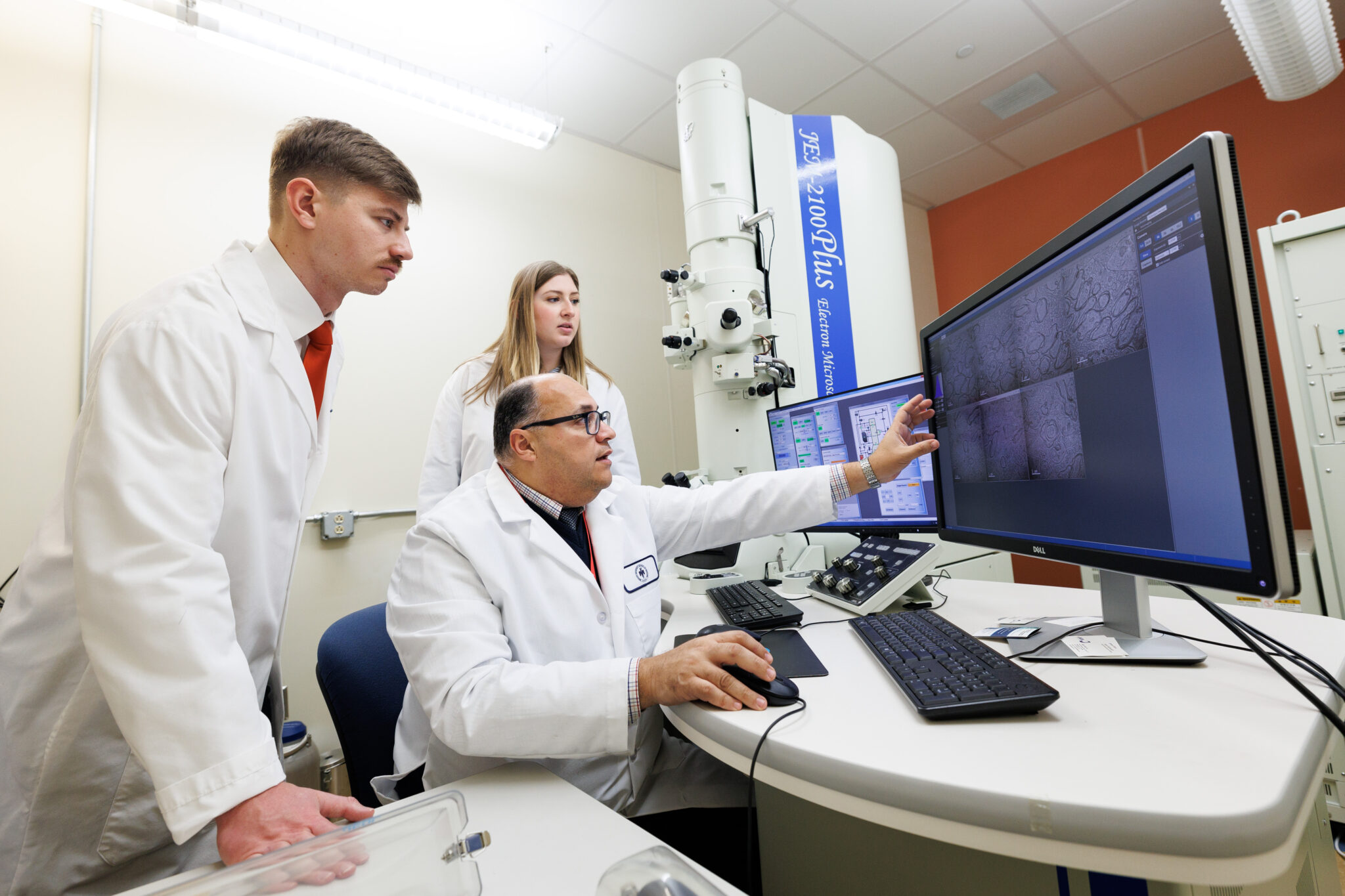 biomedical sciences researcher and students working with electron microscope