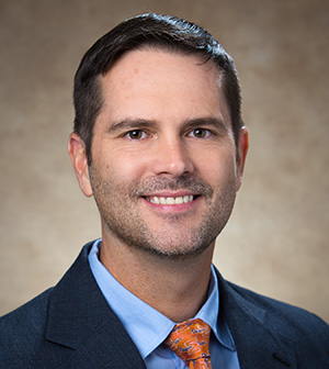 Dr. Joe Hayes in blue suit smiles for headshot