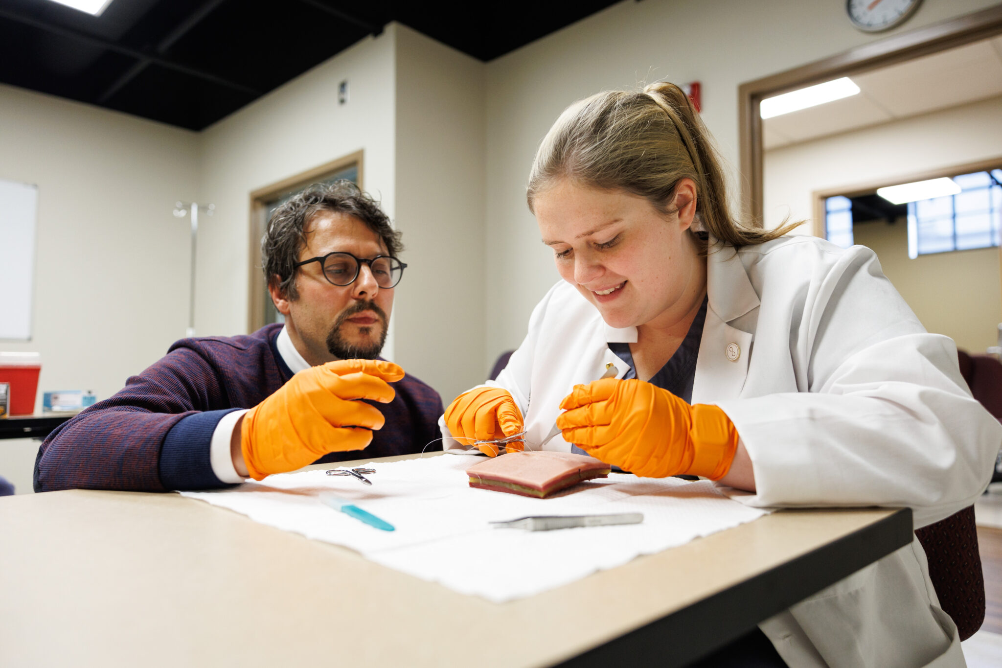 medical student practicing suturing on a simulation tool