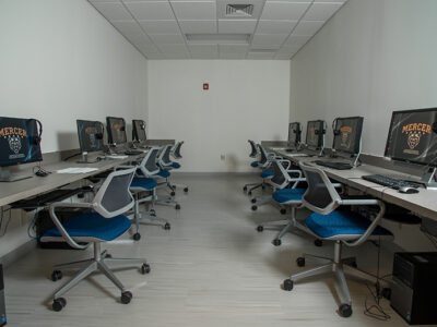 Room with two long tables an up to 8 computers with chairs.