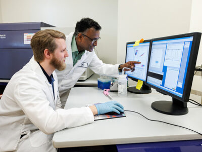 Professor pointing at the computer screen instructing student.