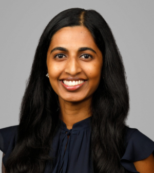 Dr. Sheila Thomas, wearing a dark blue top, smiles in front of a gray background.