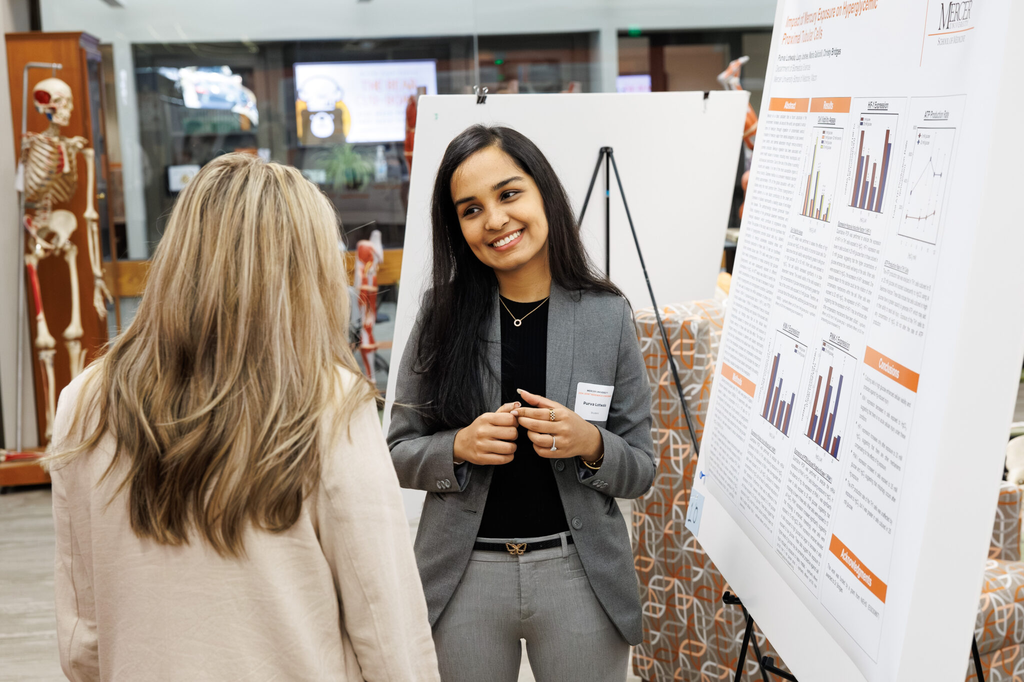 smiling woman stands in front of research poster