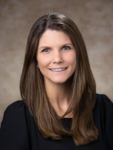 Woman with brown hair in black shirt smiles. 