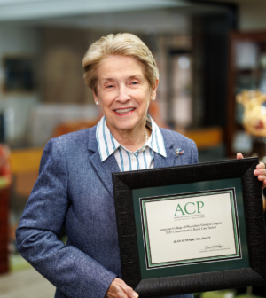 Jean Sumner, MD, MACP smiles with Georgia ACP award in medical library