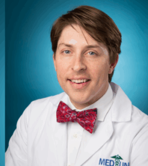 Dr. Daniel Gordon wears a red bow tie and white coat in front of a blue background.