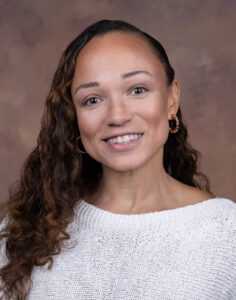 Dr. Stephanie Satchell smiles in front of a brown backdrop.